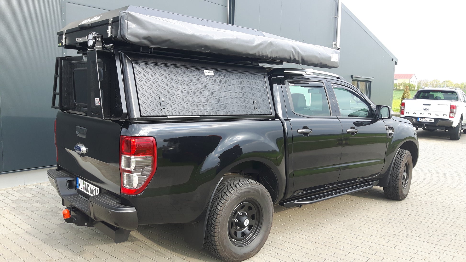 Hardtop Alu-Cab Adventure pour Isuzu D-Max 2021+ en aluminium, vue de face, avec fenêtres latérales et fixation robuste.